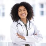 Doctor, black woman and smile portrait for healthcare with life insurance in hospital for wellness.